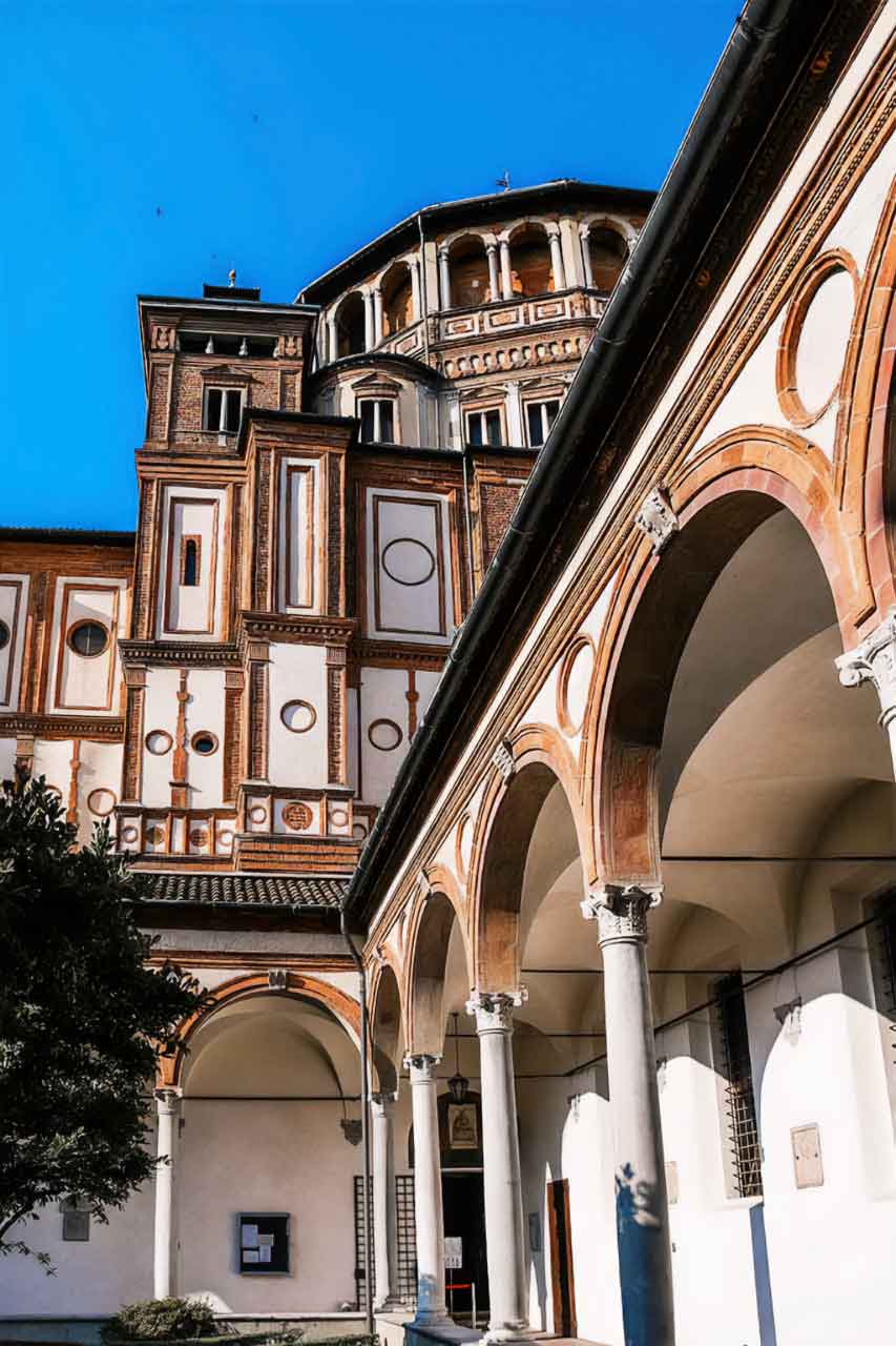 Widok na kościół Santa Maria delle Grazie z krużganka, ukazujący architekturę i detal fasady, znany z fresku „Ostatnia Wieczerza” autorstwa Leonarda da Vinci.