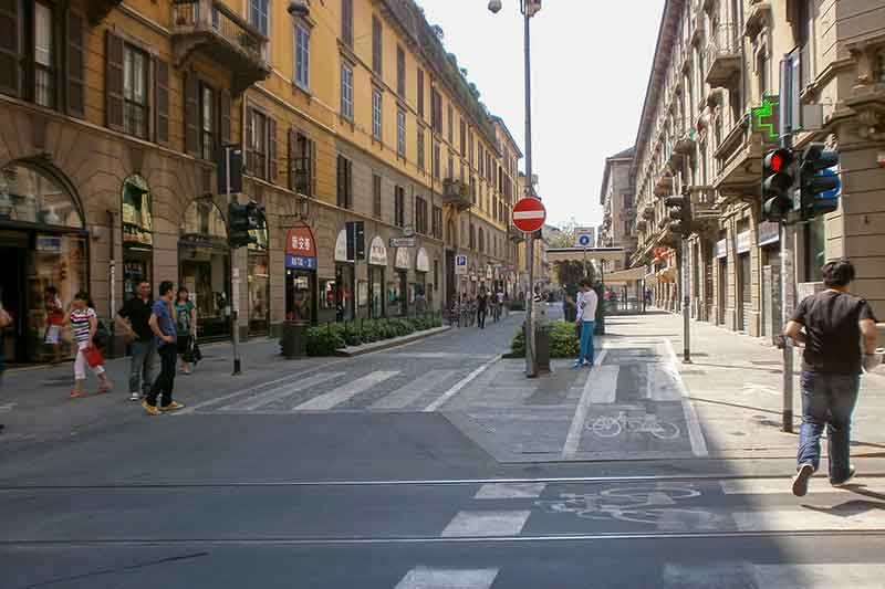 Via Paolo Sarpi w Mediolanie, tętniąca życiem ulica pełna sklepów, restauracji i spacerujących pieszych, znana z dynamicznej atmosfery.