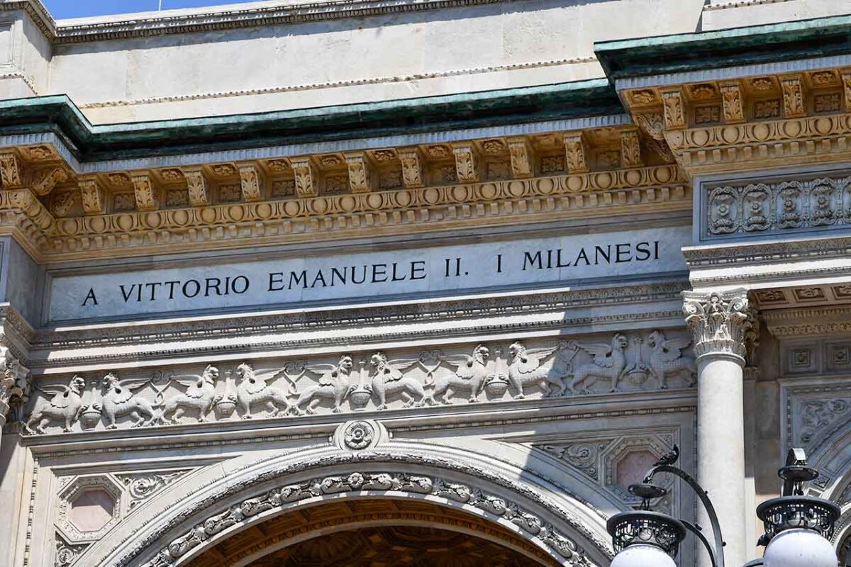 Napis "A Vittorio Emanuele - I milanesi" umieszczony nad wejściem do Gallerii Vittorio Emanuele II w Mediolanie, oddający hołd Wiktorowi Emanuelowi II, pierwszemu królowi Włoch.