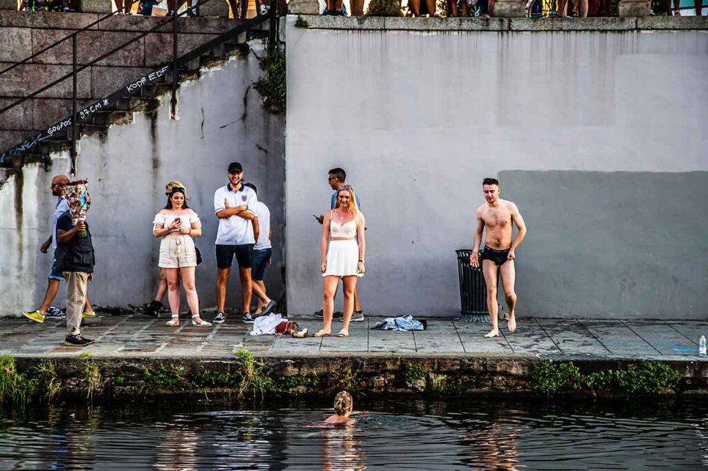 Ludzie kąpiący się w Naviglio, Mediolan. Obraz przedstawia osobę zanurzoną w wodzie kanału. 