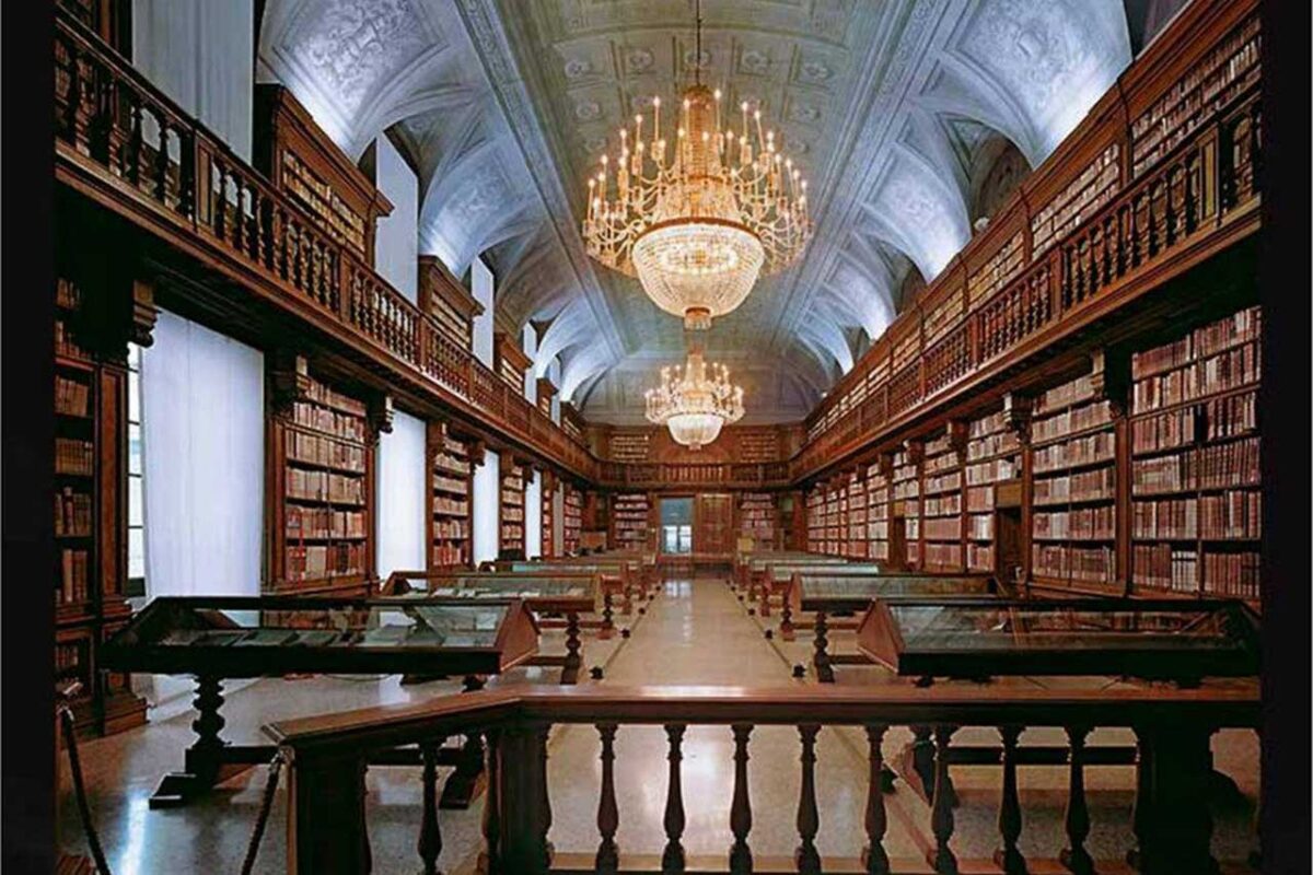 The reading room of the Braidense Library in Milan, with tall bookshelves full of books, elegant chandeliers, and a decorated ceiling.