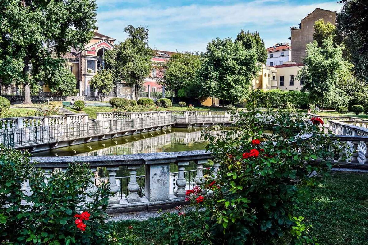 A pond in the Giardino della Guastalla park in Milan, surrounded by greenery and flowers