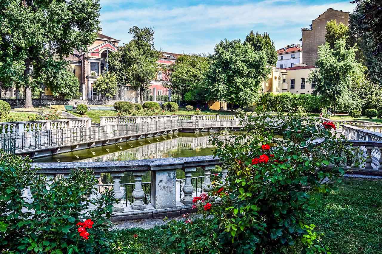 Staw w parku Giardino della Guastalla w Mediolanie, otoczony zielenią i kwiatami