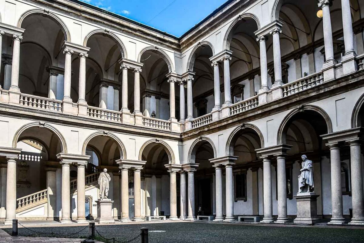 Dziedziniec Pinakoteki Brera w Mediolanie, miejsce otoczone budynkami galerii, z przestrzenią do odpoczynku i podziwiania architektury.