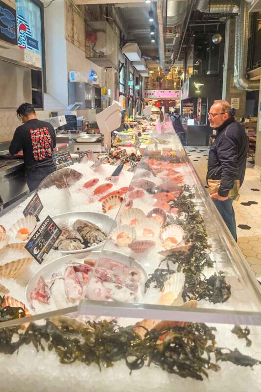 Stoisko na Mercato Centrale w Mediolanie, oferujące lokalne produkty i specjały kulinarne w nowoczesnej przestrzeni targowej.