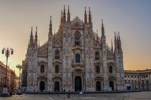 Katedra Duomo w Mediolanie o poranku, skąpana w ciepłym świetle wschodzącego słońca