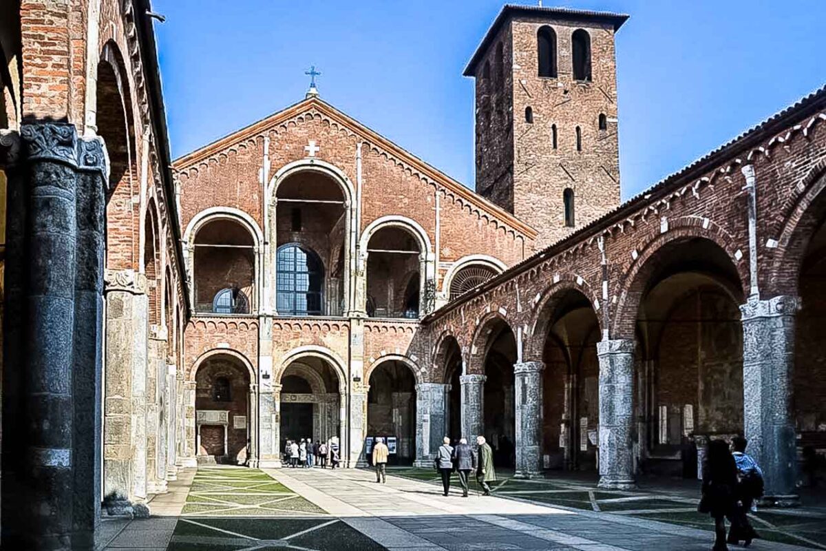 Wewnętrzny krużganek Bazyliki św. Ambrożego w Mediolanie, otoczony arkadami i pełen spokojnej, zabytkowej atmosfery.
