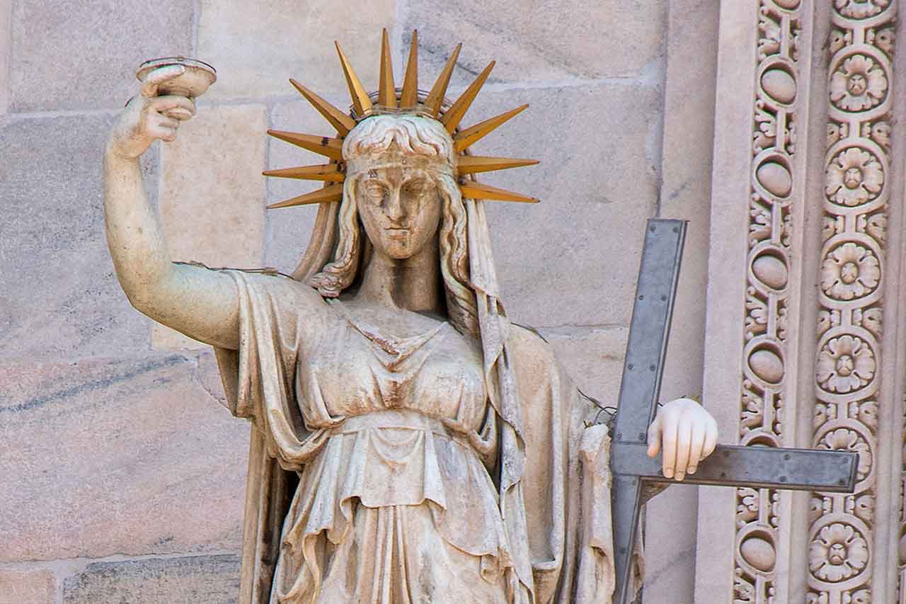 Rzeźba na fasadzie Duomo di Milano, przedstawiająca postać kobiety z pochodnią, uznawana za możliwą inspirację dla nowojorskiej Statuy Wolności.