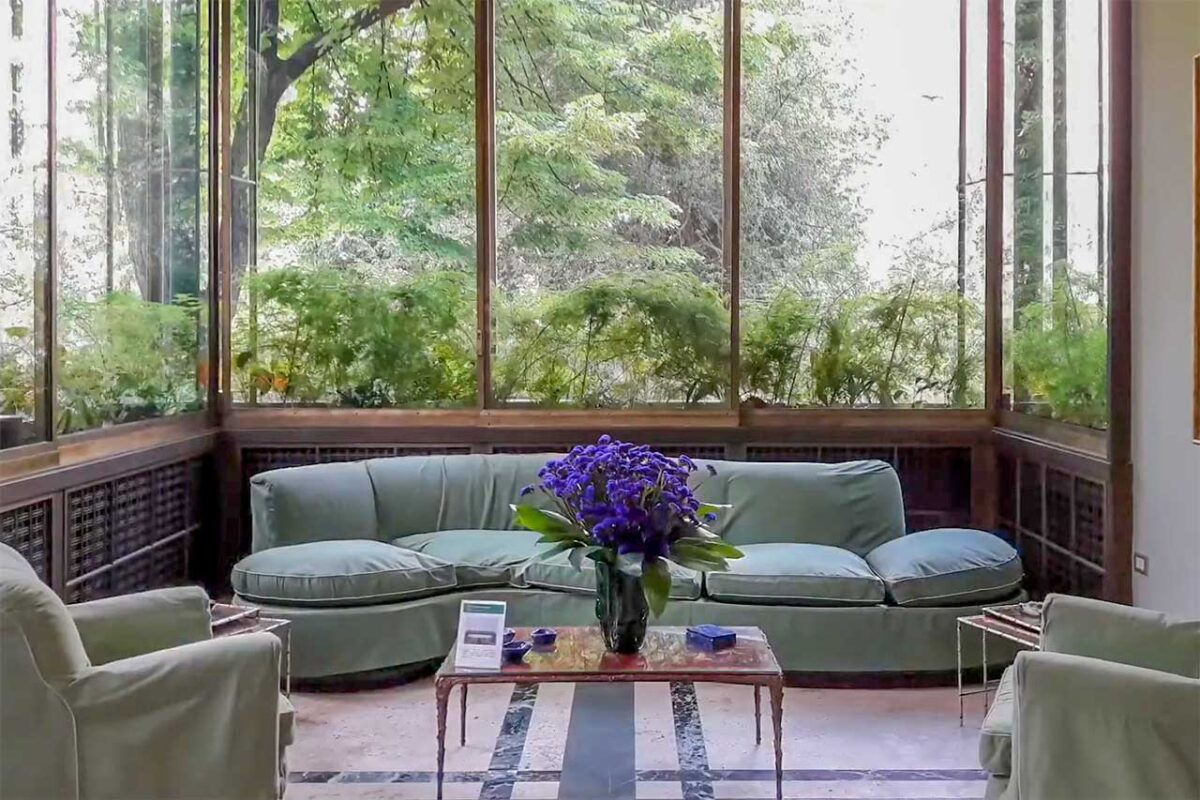 Wnętrze willi Necchi Campiglio w Mediolanie z sofą i dużymi oknami na ogród